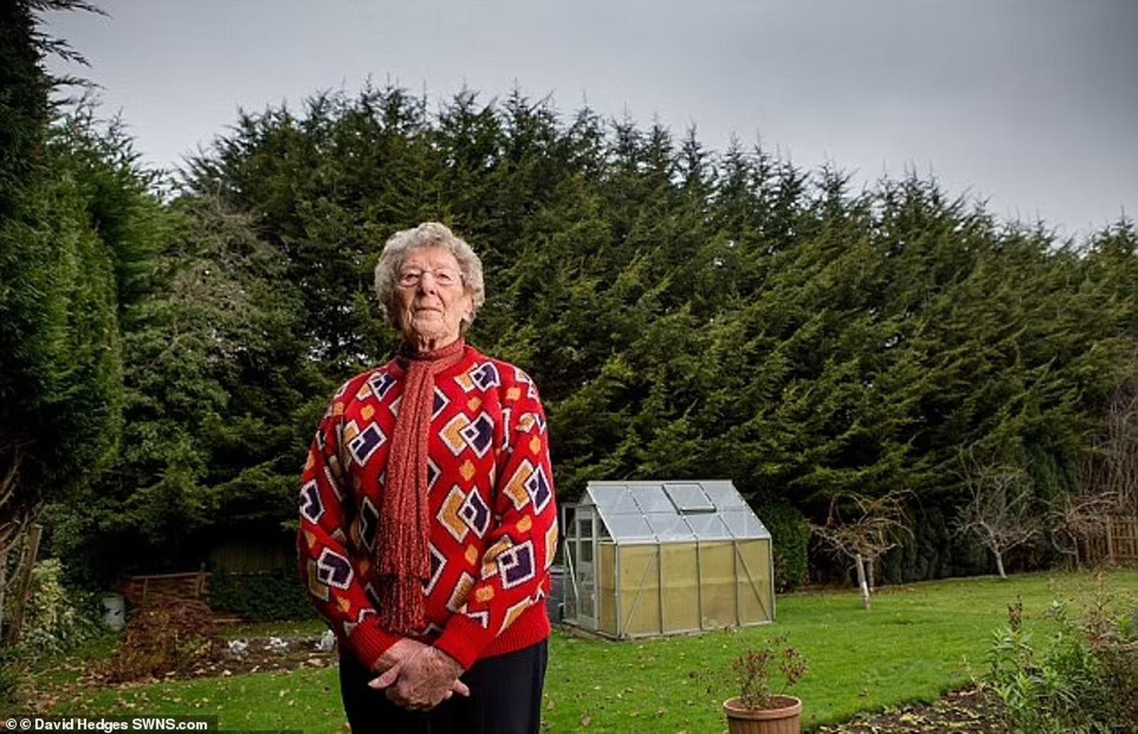 Val Horton standing in her garden in front of a fifty-foot leylandii hedge