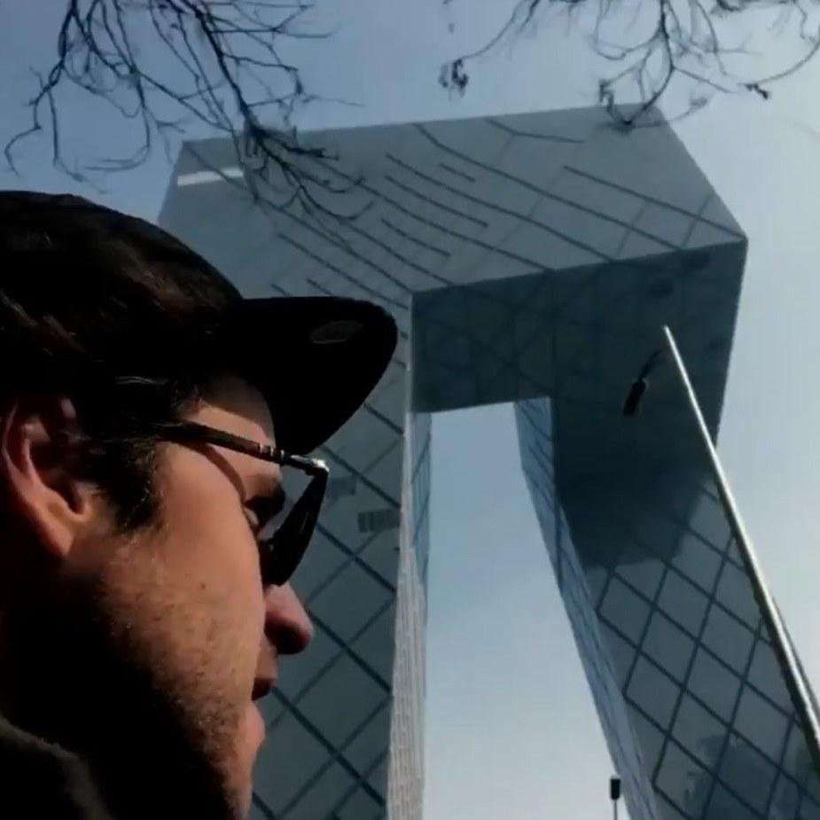 Danny in a cap and sunglasses in front of the CCTV headquarters in Beijing