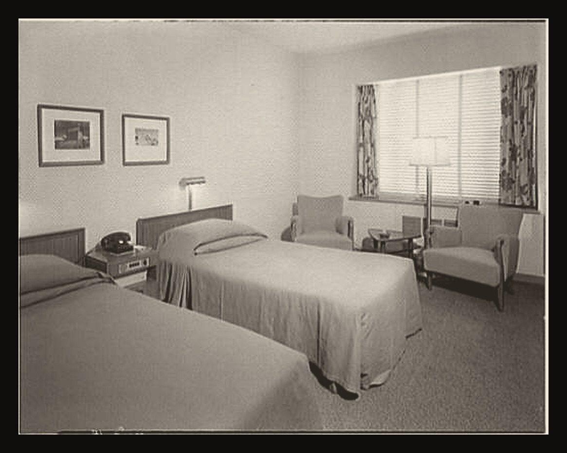 A Statler hotel room in Washington in 1954: bed against the side wall, desk, armchair and window at the far end