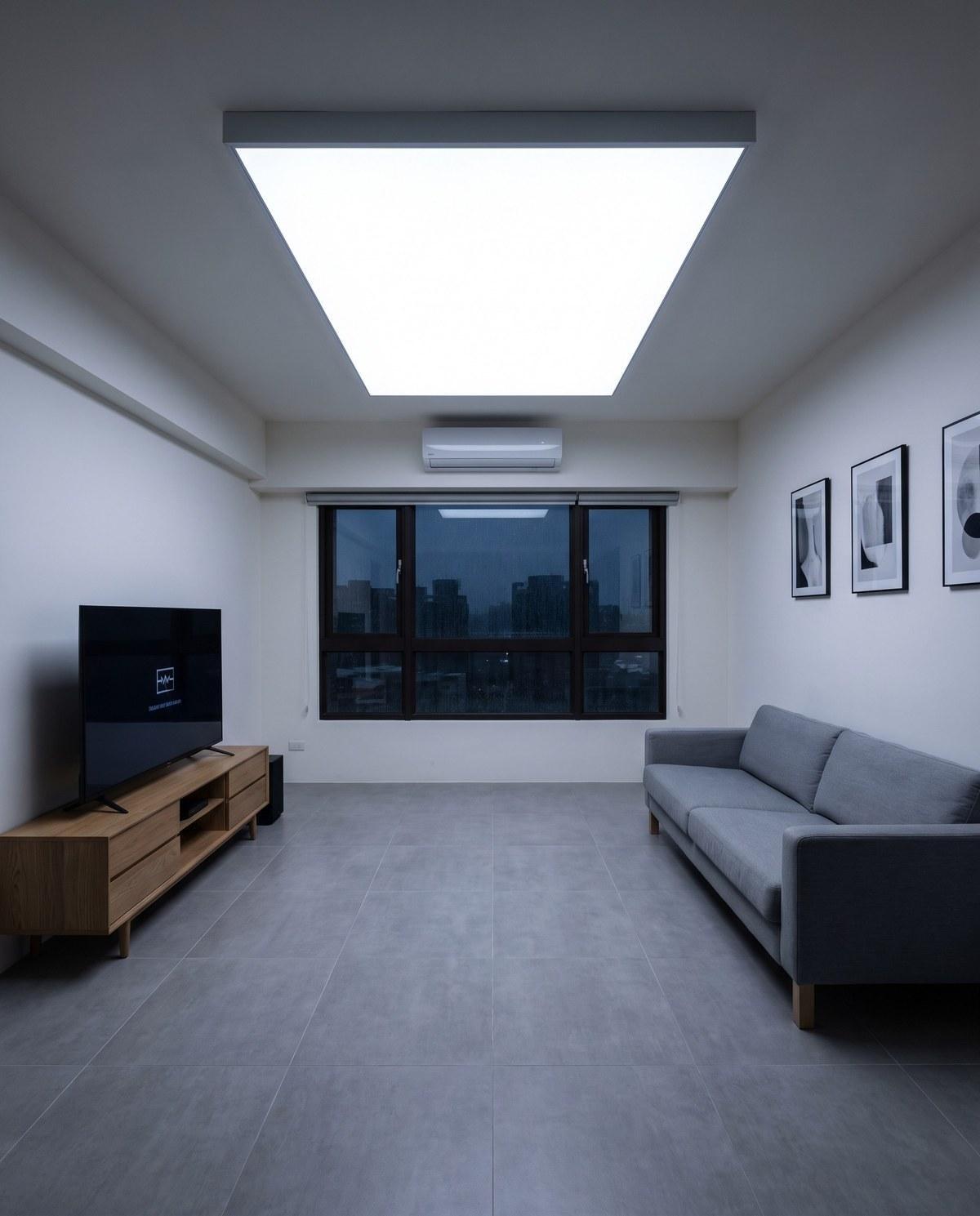 A living room lit by a large square LED ceiling panel