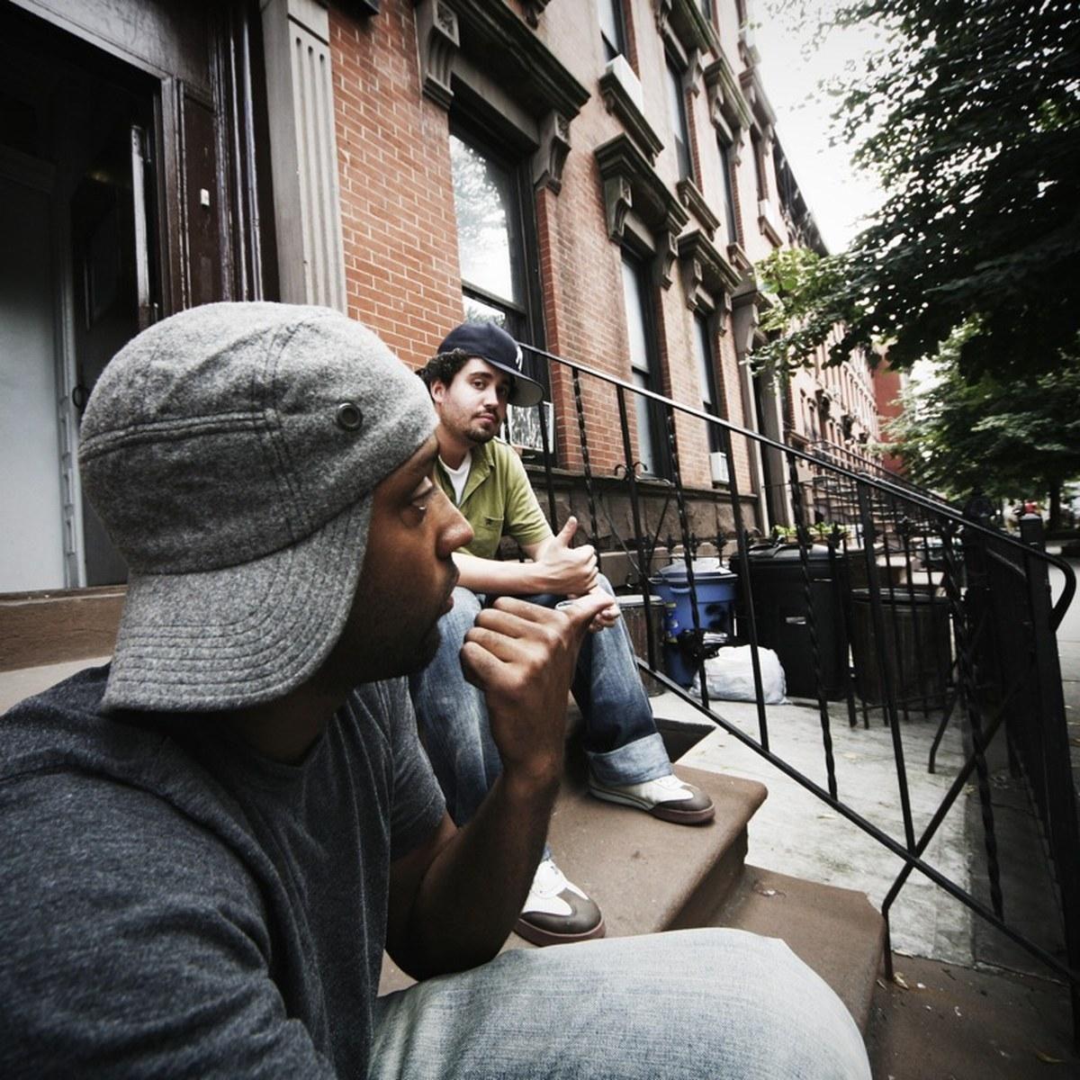 Two men sitting and talking on the stoop of a Brooklyn brownstone
